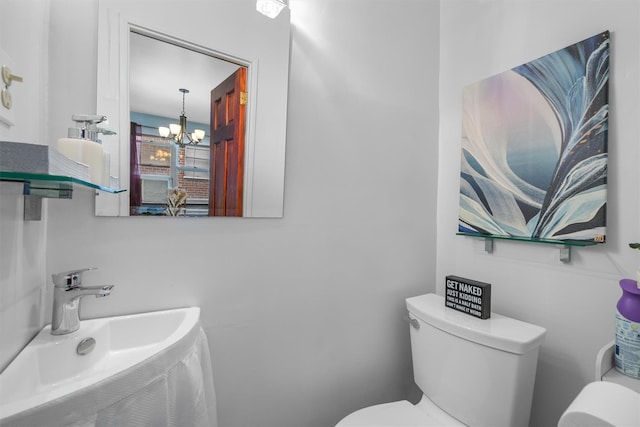 bathroom with toilet, an inviting chandelier, and sink