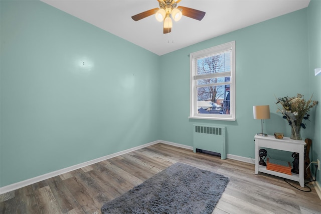 unfurnished room featuring ceiling fan, light wood-type flooring, and radiator