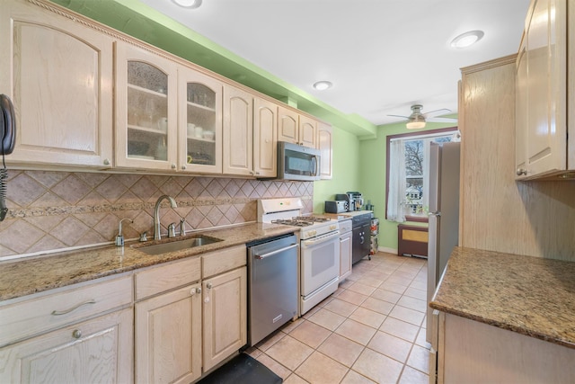 kitchen featuring light stone countertops, appliances with stainless steel finishes, ceiling fan, sink, and light tile patterned floors