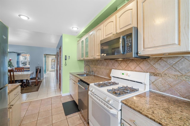 kitchen with sink, backsplash, light brown cabinetry, light tile patterned floors, and appliances with stainless steel finishes