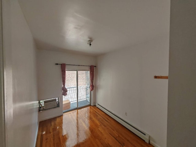 empty room featuring baseboard heating, hardwood / wood-style floors, and a wall mounted air conditioner