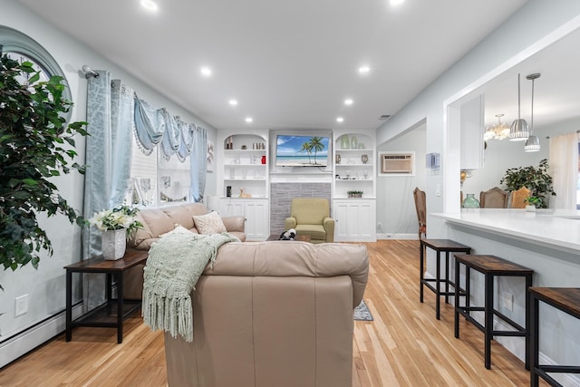 living room featuring built in features, a baseboard radiator, and light wood-type flooring