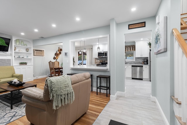 living room featuring light wood-type flooring and an AC wall unit