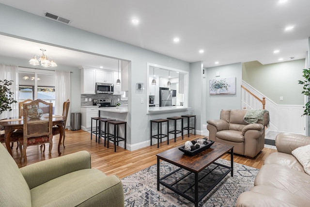 living room with light hardwood / wood-style flooring and an inviting chandelier