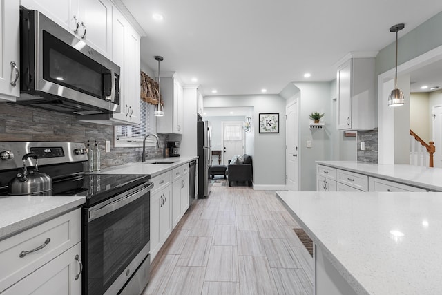 kitchen featuring white cabinets, appliances with stainless steel finishes, hanging light fixtures, and sink