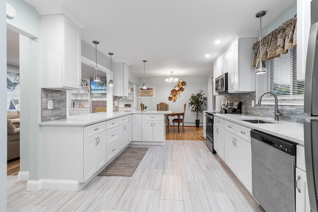 kitchen with kitchen peninsula, decorative backsplash, stainless steel appliances, sink, and white cabinets