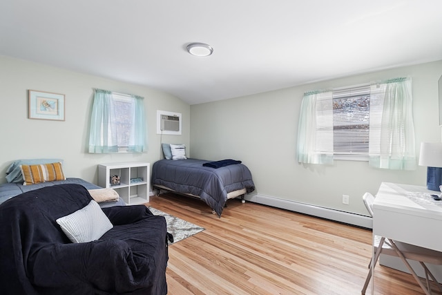 bedroom with hardwood / wood-style floors, a wall unit AC, and a baseboard heating unit