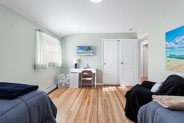 bedroom with a closet, a baseboard radiator, lofted ceiling, and hardwood / wood-style flooring