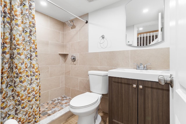 bathroom featuring vanity, toilet, tiled shower, and tile walls