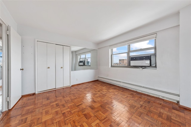 unfurnished bedroom with a baseboard heating unit, cooling unit, dark parquet floors, and a closet