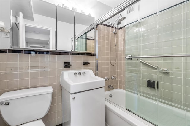 full bathroom featuring tile walls, shower / bath combination with glass door, decorative backsplash, vanity, and toilet