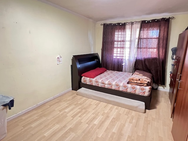 bedroom featuring crown molding and light hardwood / wood-style flooring