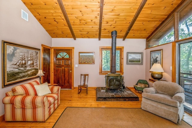 living room with wooden ceiling, a wood stove, light hardwood / wood-style flooring, and lofted ceiling with beams