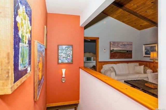 hallway with wooden ceiling, wooden walls, and vaulted ceiling with beams