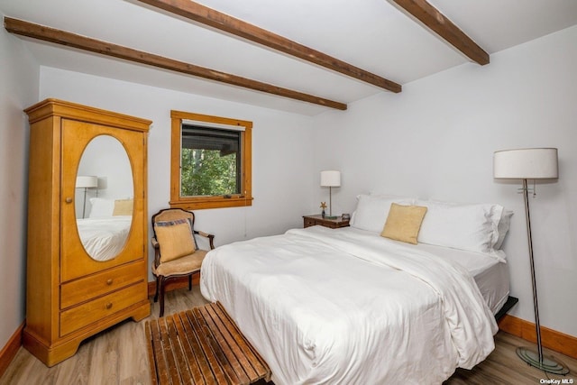 bedroom featuring beam ceiling and light wood-type flooring