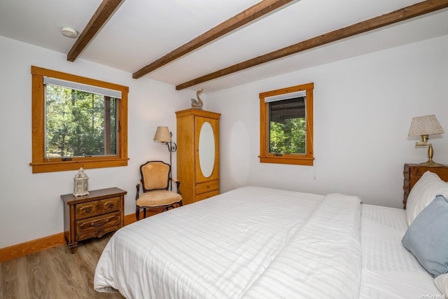 bedroom featuring beamed ceiling and light wood-type flooring