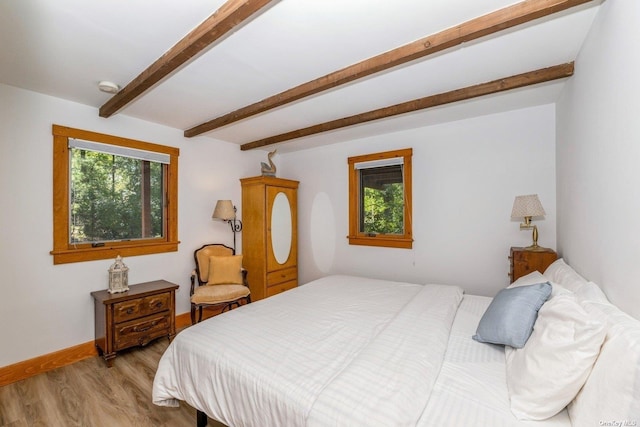 bedroom with light hardwood / wood-style floors and beamed ceiling