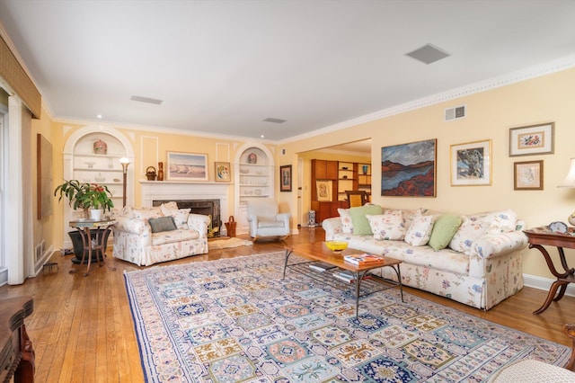 living room with light wood-type flooring, built in features, and crown molding