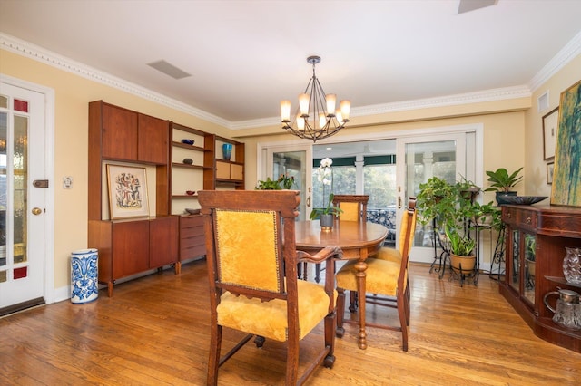 dining room featuring ornamental molding, light hardwood / wood-style floors, and a notable chandelier