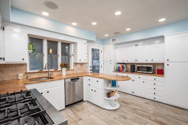 kitchen featuring kitchen peninsula, white cabinetry, sink, and stainless steel appliances