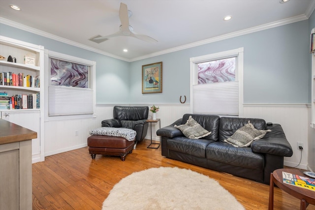 living room featuring ceiling fan, built in features, ornamental molding, and light hardwood / wood-style flooring