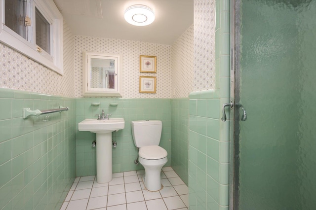 bathroom with tile patterned flooring, sink, toilet, and tile walls