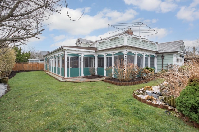 back of house with a sunroom and a lawn