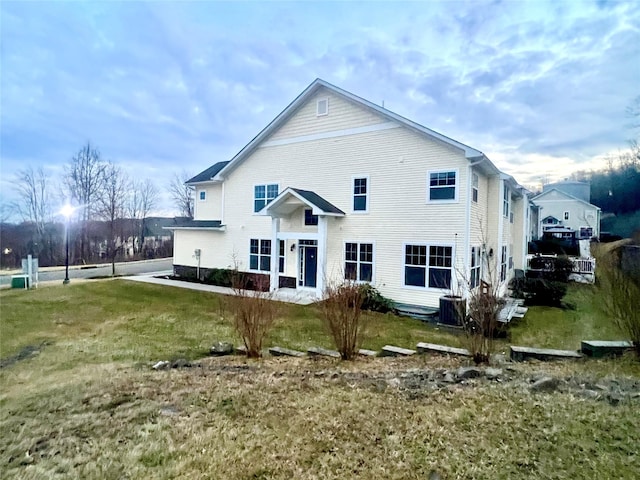 rear view of property featuring cooling unit and a lawn