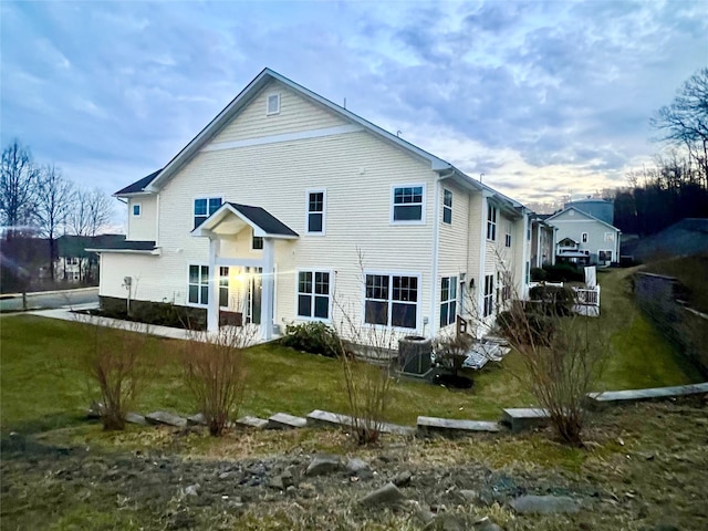 back of house with central AC and a yard