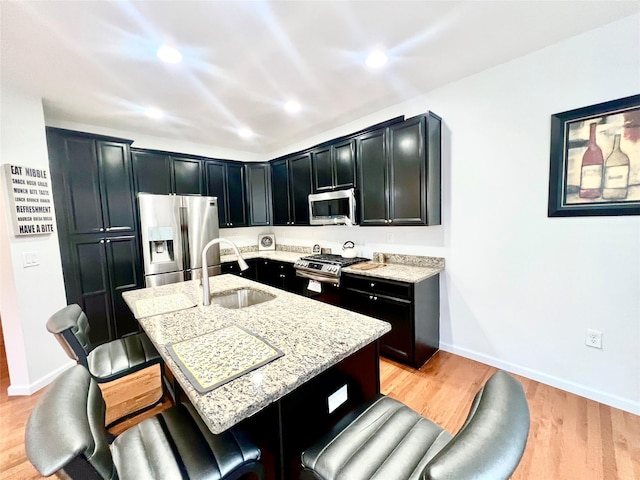 kitchen featuring an island with sink, appliances with stainless steel finishes, a breakfast bar, and sink