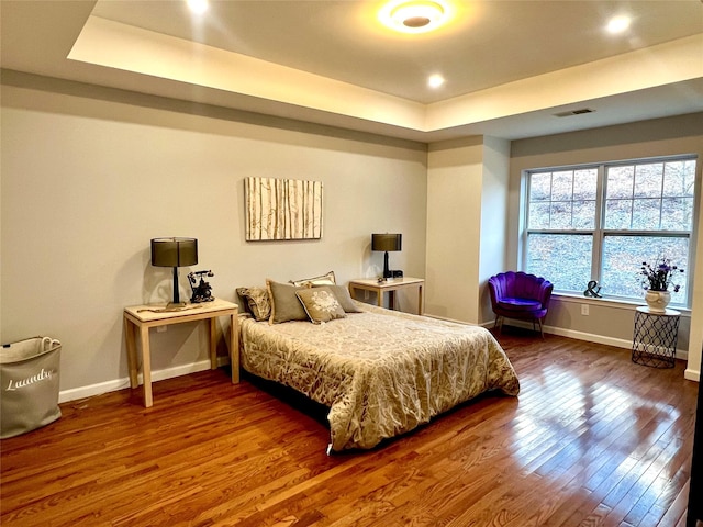 bedroom featuring wood-type flooring and a tray ceiling