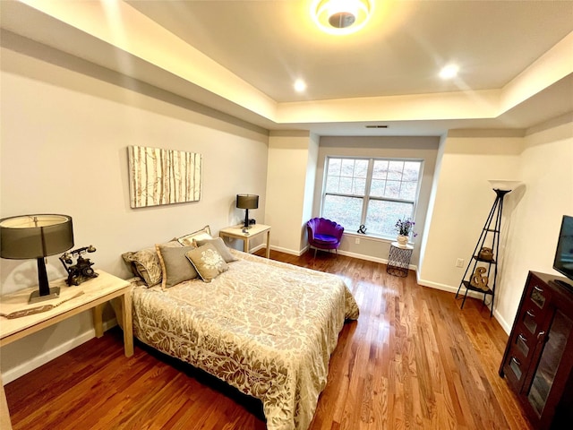 bedroom featuring hardwood / wood-style flooring and a raised ceiling