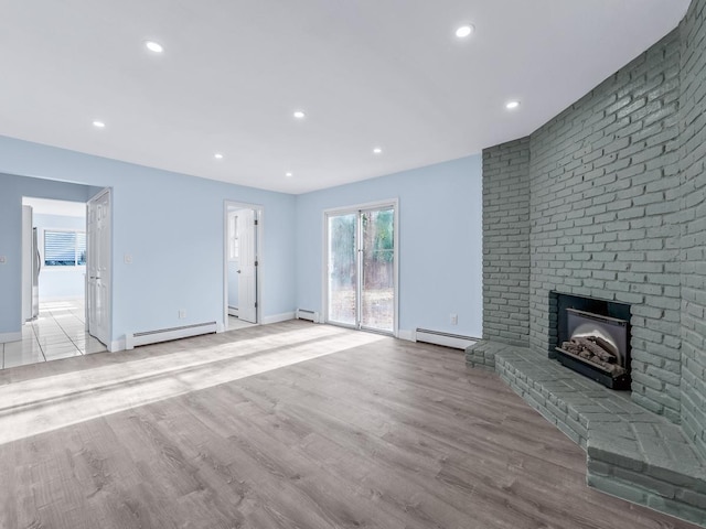 unfurnished living room with a fireplace, light hardwood / wood-style flooring, and a baseboard heating unit