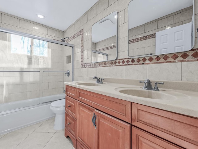 full bathroom featuring combined bath / shower with glass door, tile patterned floors, toilet, vanity, and tile walls