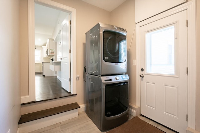 laundry room with light hardwood / wood-style flooring and stacked washer and clothes dryer