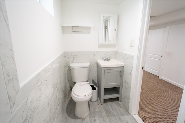 bathroom featuring vanity, toilet, and tile walls