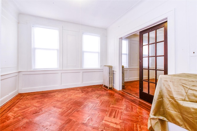 unfurnished bedroom with parquet flooring, french doors, a closet, and radiator