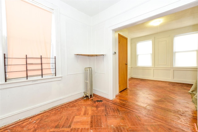 empty room featuring radiator heating unit and parquet floors