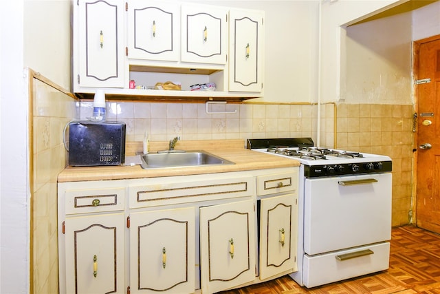 kitchen featuring sink, white gas range oven, white cabinetry, and light parquet flooring