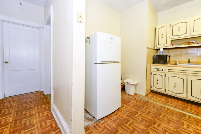 kitchen featuring backsplash, sink, white refrigerator, light parquet flooring, and white cabinetry