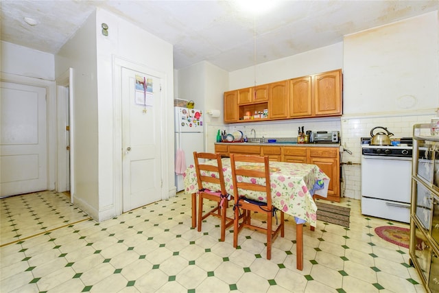 kitchen featuring decorative backsplash, white appliances, and sink