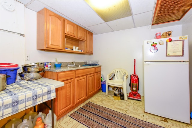 kitchen featuring a drop ceiling and white fridge