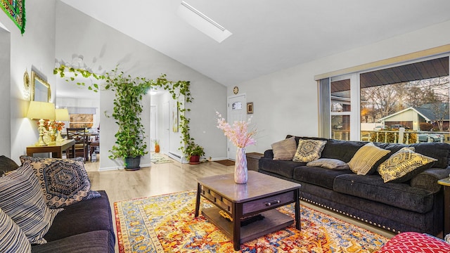 living room featuring lofted ceiling with skylight and light hardwood / wood-style floors