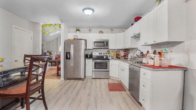 kitchen featuring white cabinets, backsplash, stainless steel appliances, and light hardwood / wood-style floors