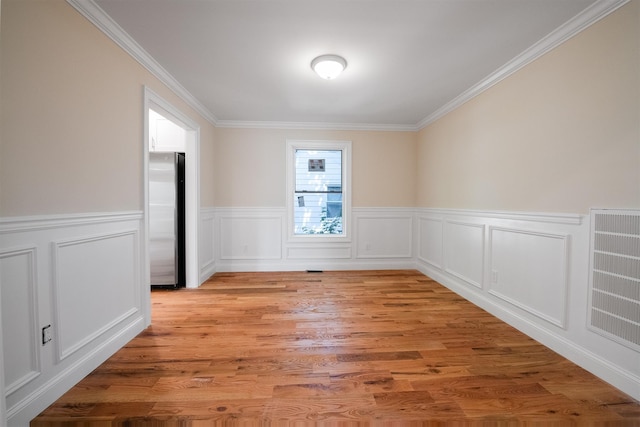 empty room featuring light wood-type flooring and ornamental molding