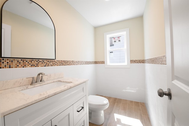 bathroom featuring vanity, toilet, and tile walls