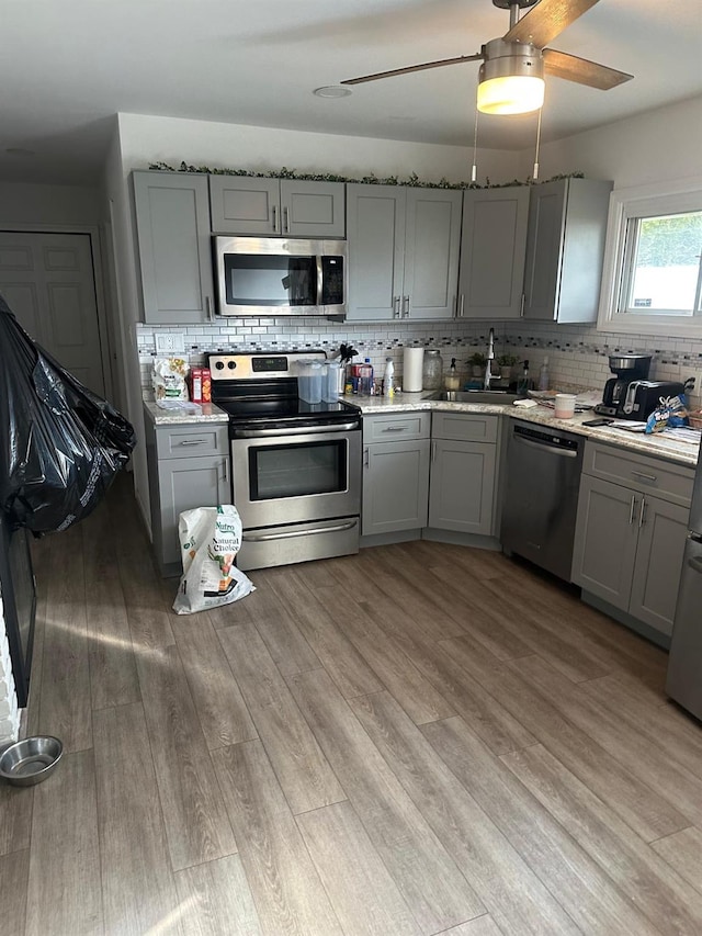 kitchen with gray cabinets, sink, light hardwood / wood-style floors, and appliances with stainless steel finishes