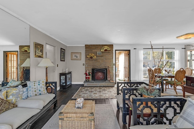 living room featuring dark hardwood / wood-style flooring, a stone fireplace, and ornamental molding