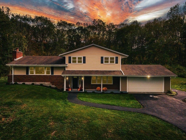 split level home with a yard, a porch, and a garage