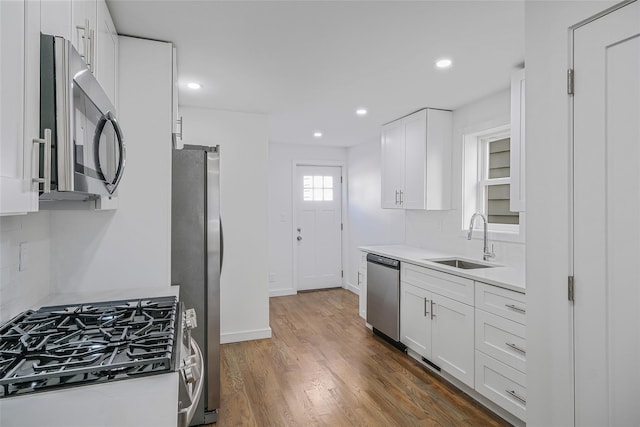 kitchen featuring backsplash, stainless steel appliances, dark wood-type flooring, sink, and white cabinets